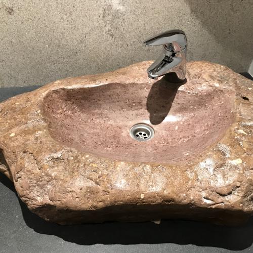 Ein Waschbecken ausgehölt aus einem Findling. Das Becken selber ist vertieft in den Findling eingearbeitet und fein geschliffen.