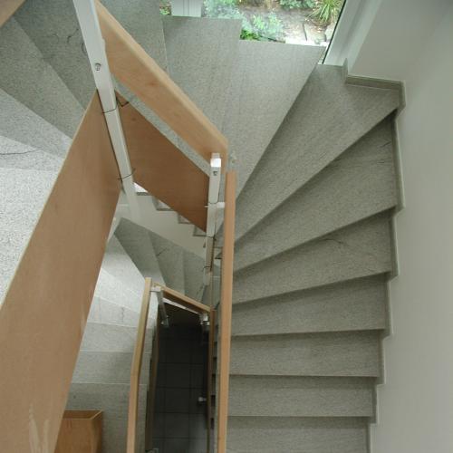 Treppenhaus aus Imperial White mit Handlauf in einer Kombination aus Holz und Edelstahl