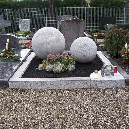Doppelgrab mit Grabeinfassung aus hellem Orion mit handwerklich bearbeiteter Oberfläche. Das Grabmal besteht aus 2 unterschiedlich großen Kugeln.