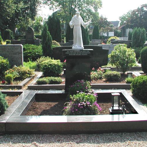 Eine Stele aus schwarzem Granit mit einem Spruch oben und einer Figur des St. Francesco aus Marmor.