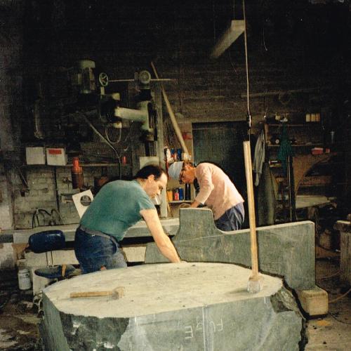 Eine Hälfte des Brunnens in der Werkstatt. Das Werkstück wird mit einem Vorschlaghammer und Sprengeisen in Form gebracht.