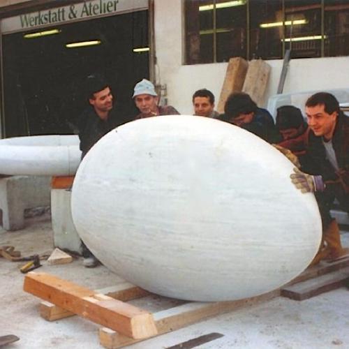 Die Mitarbeiter der Firma rollen das Ei über zur weiteren bearbeitung über 2 Holzbalken.